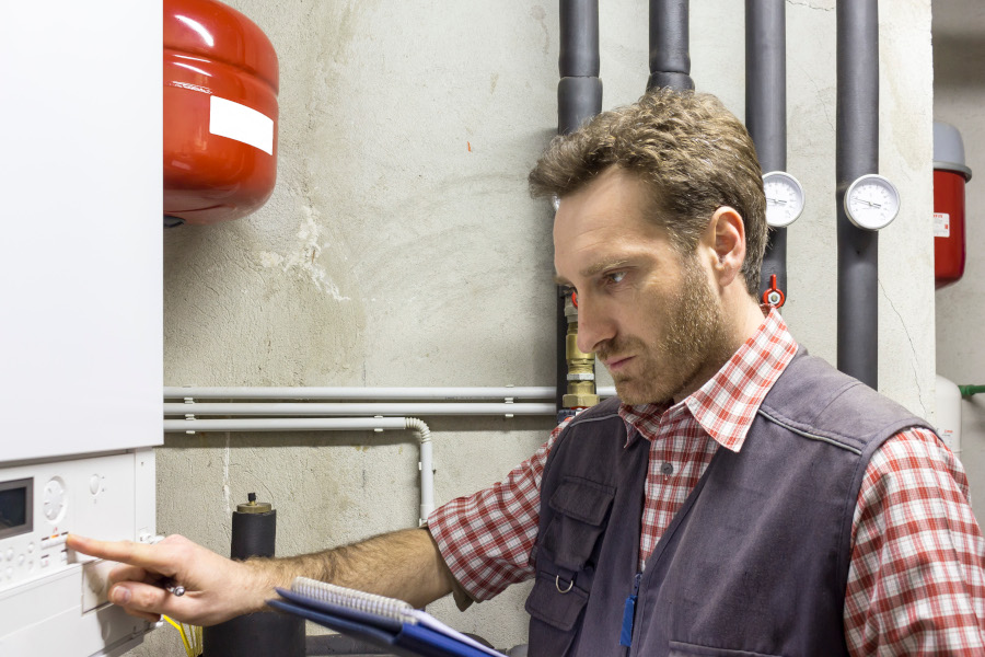 Chauffagiste méticuleux en train de préparer le chauffage pour l'hiver. Il vérifie les filtres, contrôle les thermostats et inspecte les conduits avec sérieux. Faire appel à un professionnel pour un entretien annuel garantit un fonctionnement optimal du système de chauffage pendant la saison hivernale.